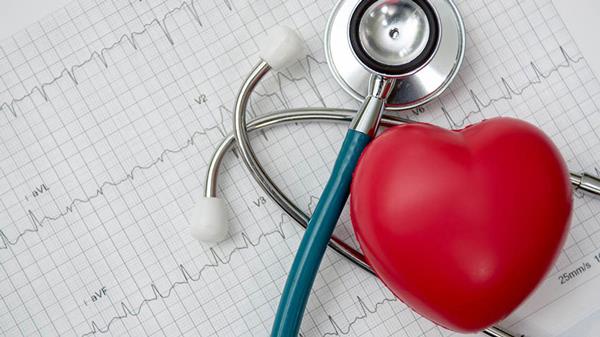 گوشی پزشکی و مولاژ قلب که هر 2 روی کاغذ نوار قلب قرار دارند