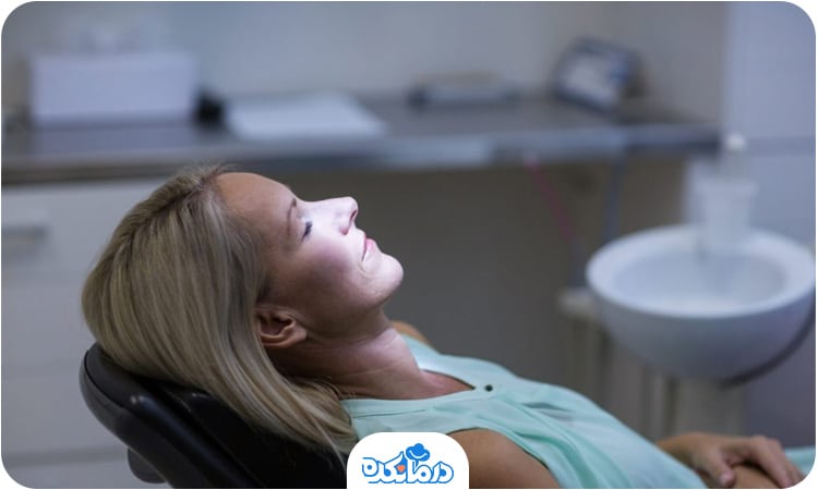 تصویر یک زن که روی یونیت دندان‌پزشکی خوابیده است